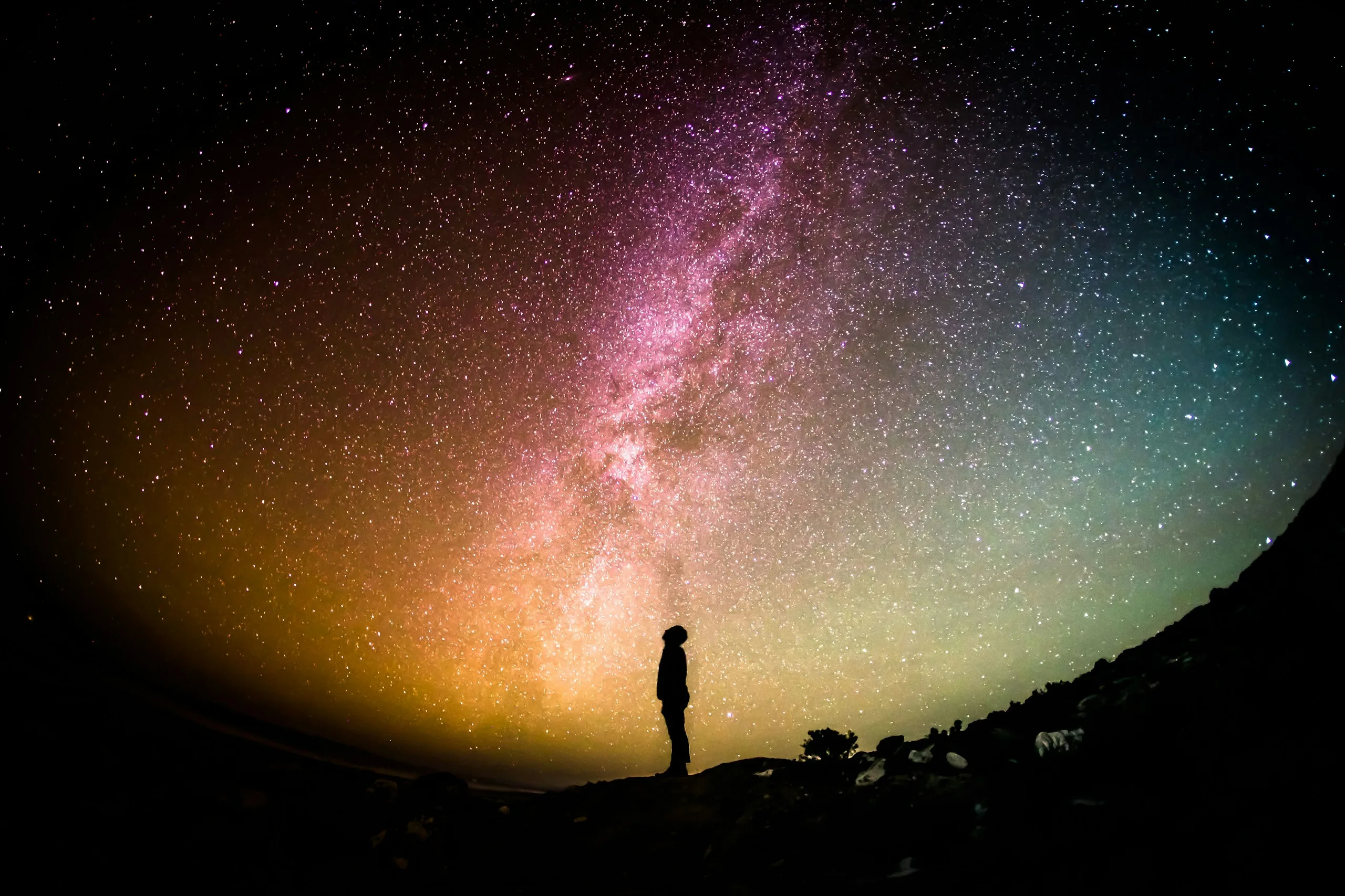 A camera on a heavy-duty tripod set up for astrophotography under the night sky